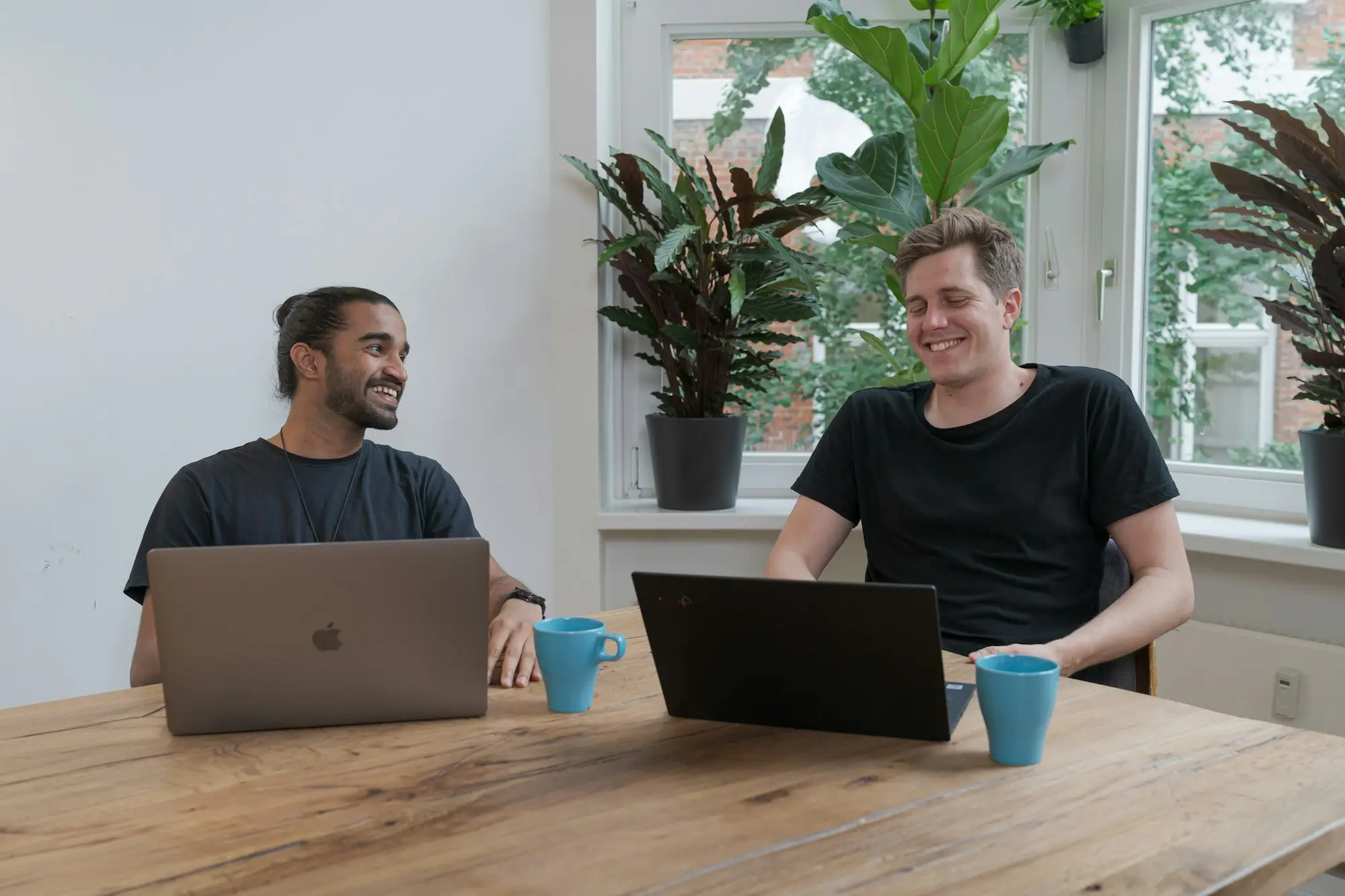 Two business owners at a timber table with laptops, working out how much working capital their business needs